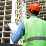 civil engineer safety hat with clipboard against construction