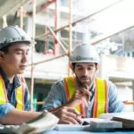 young asian engineers caucasian engineer colleagues site inspector discuss together using notebook computer paper blueprint building construction sitehome renovation ideas concept